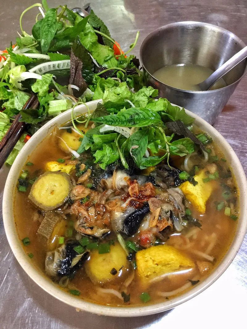 Bun oc snail rice vermicelli soup with tomatoes and herbs in Hanoi